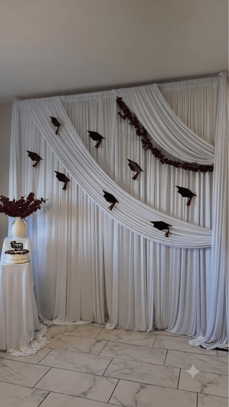 Graduation celebration backdrop with draped fabric and cake table