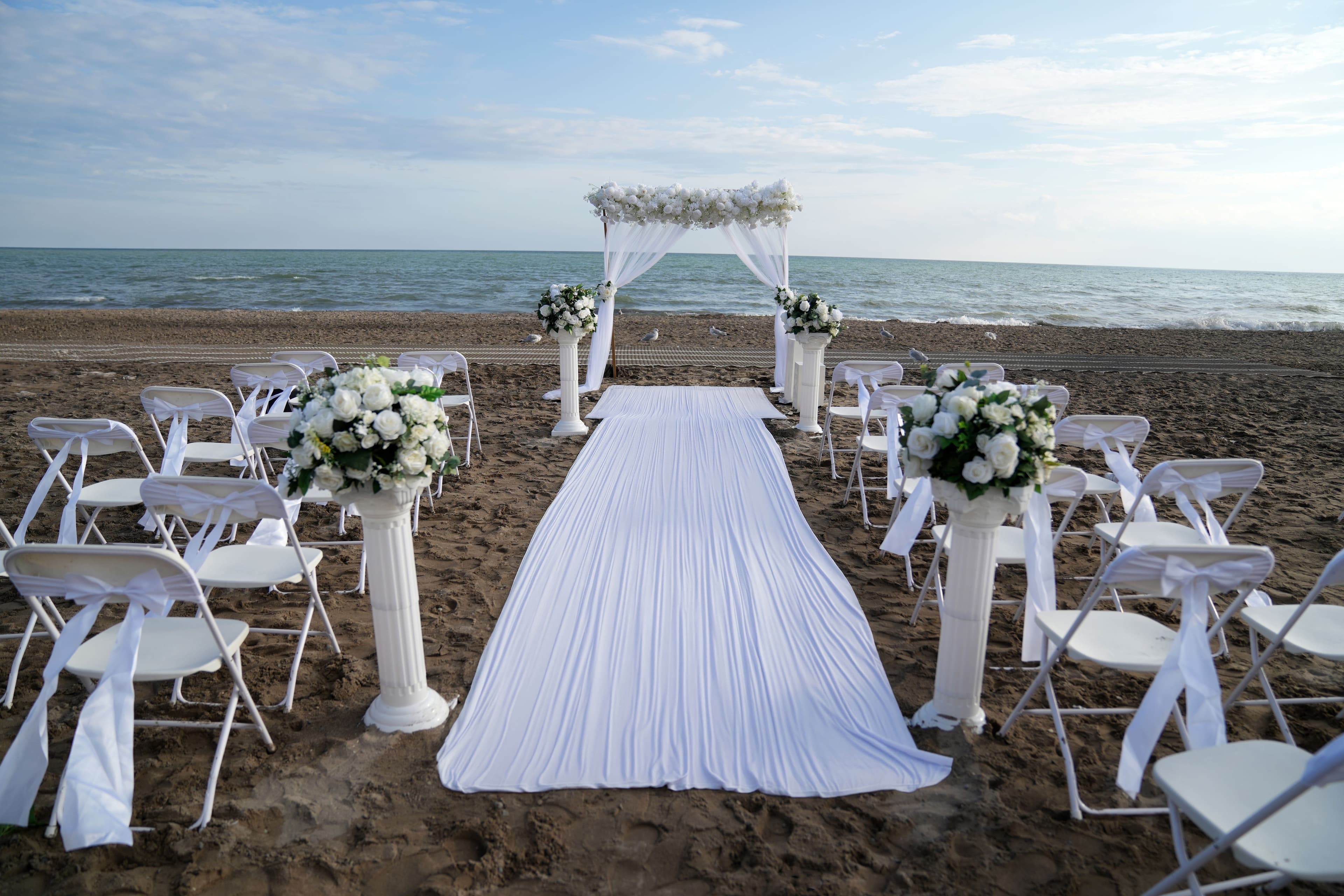 Beach wedding ceremony with a white floral arch and ocean view