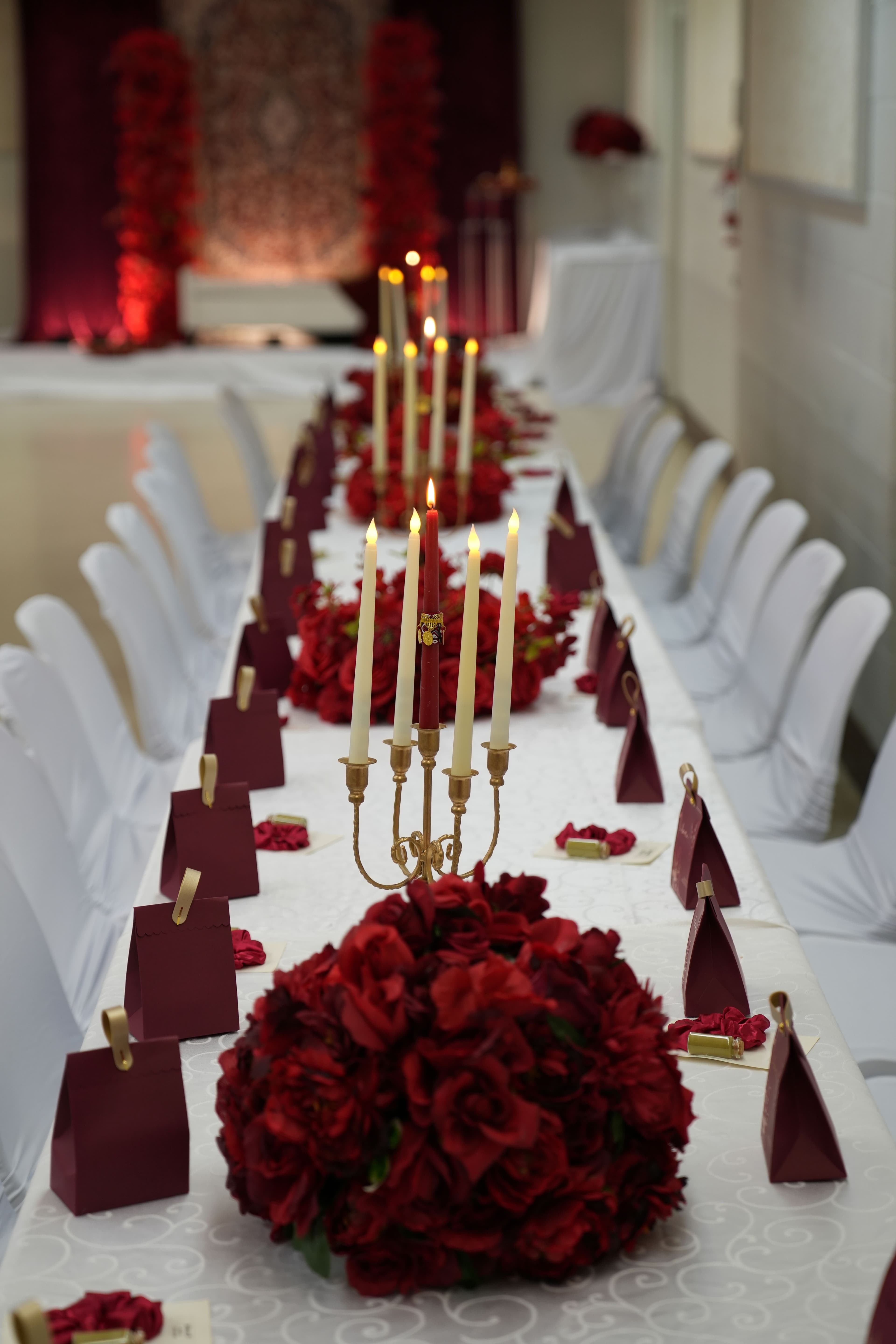 Candlelit wedding table dressed with burgundy roses and ivory linens